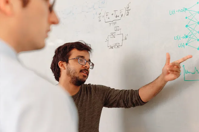 a researcher points to a formula on the whiteboard